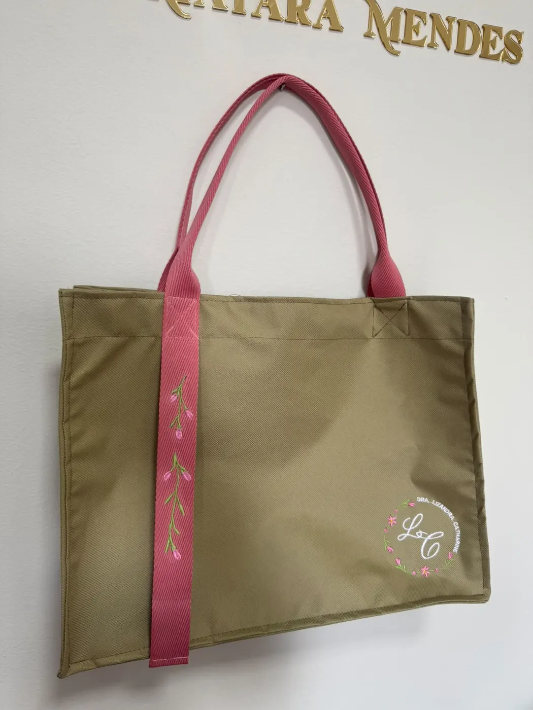 Bolsa caqui com alça rosa bordada com raminhos floridos e monograma LC em guirlanda