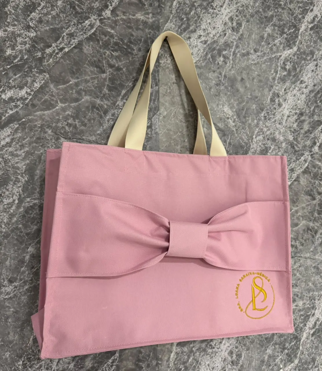 Bolsa rosa modelo Laço com alça bege e monograma SL bordado em dourado