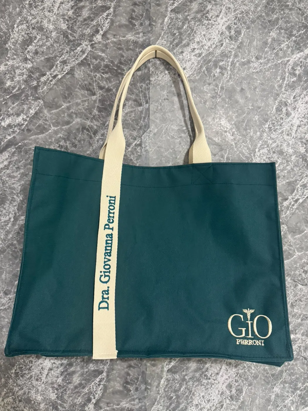 Bolsa verde petróleo com alça cru bordada “Dra. Giovanna Perroni” e logo GIO